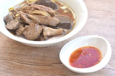 Karaciğer ve kanla kaynamış ördek eti ve siyah soya fasulyesi çorbası. Baharatlı acı biber sosu.