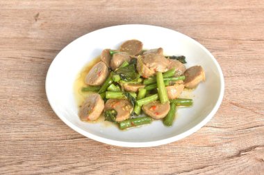 Baharatlı kızarmış et köftesi. Birkaç dilim fasulye. Tabakta fesleğen var.