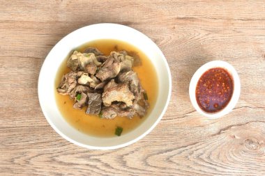 Haşlanmış et ve tendon, baharatlı acı biber soslu, tabakta kahverengi çorba.