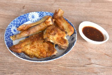 Kızarmış tavuk eti kanadı ve bacağı tabakta tatlı ve baharatlı sosa batırılmış.