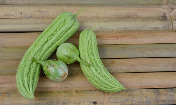 Calabaza amarga y planta de huevo en escritorio de bambú — Foto de Stock