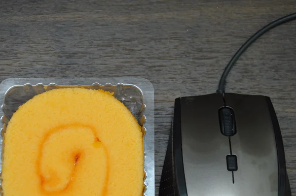 Turuncu kek rulo ve bilgisayar fare — Stok fotoğraf