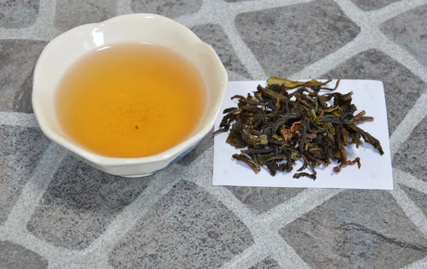 Taza de té y hoja de té sobre papel — Foto de Stock