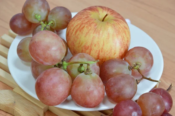 Apfel und rote Trauben auf dem Teller — Stockfoto