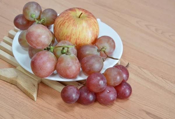 Manzana y uva roja en el plato — Foto de Stock