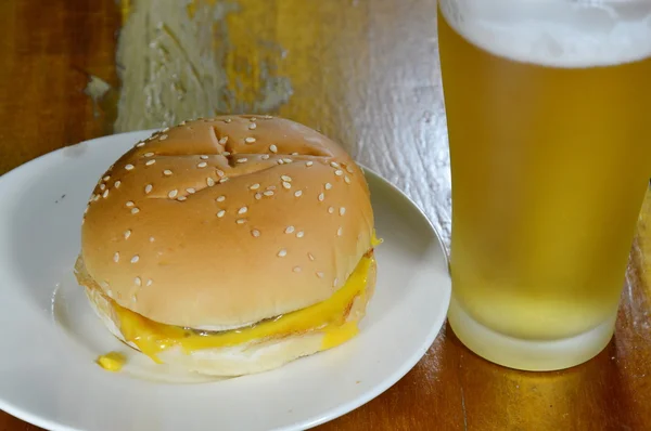 Cheeseburger en bier op tafel — Stockfoto