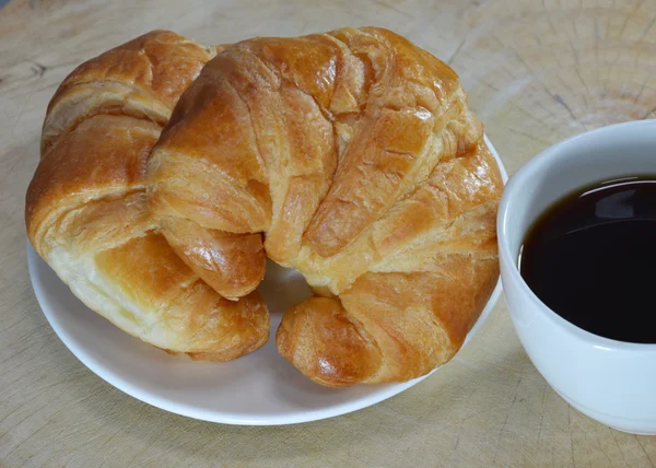 Croissant på skålen och svart kaffe — Stockfoto