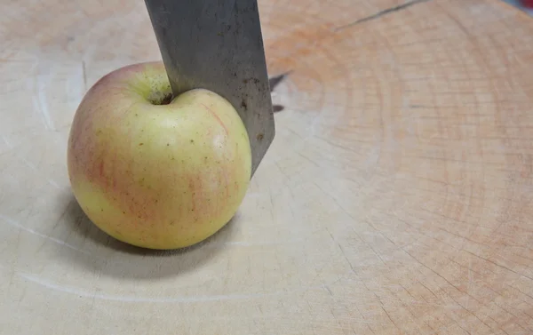 Нож, разрезанный на яблоке на деревянном блоке — стоковое фото