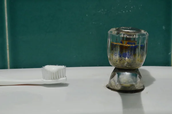 Tandkräm på tandborsten och gamla kranen på vitt handfat badrum — Stockfoto