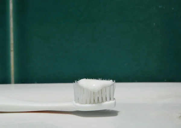 Toothpaste on toothbrush in white sink bathroom — Stock Photo, Image