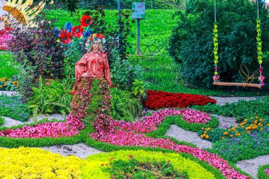 Creative flower design with a Forest Girl statue and multicolored flowerbeds in spring at flower show. Flower exhibition, City Garden serves as a community resource. Photographers were allowed to photograph for Commercial use.