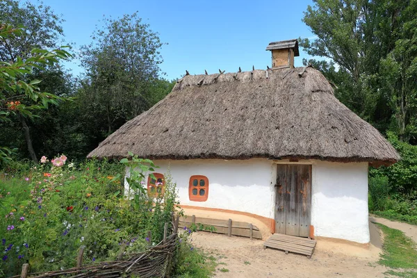 Prigovo, Kiev, Ukrayna 'daki açık hava müzesinde saman çatılı geleneksel Ukrayna kırsal kulübesi. Yaz doğasıyla çevrili otantik yalnız kulübenin atmosferik fotoğrafı..