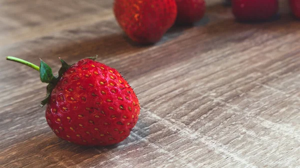 Strawberries in focus on a wooden background and a few blurry in the distance