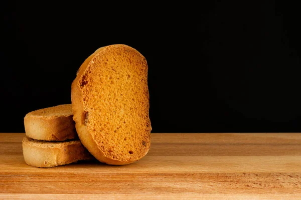 Croutons fritos dulces con pasas sobre tabla de madera y fondo negro —  Fotos de Stock