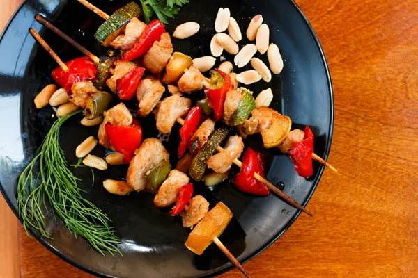 Chicken kebabs with zucchini and paper on black plate — Stock Photo, Image