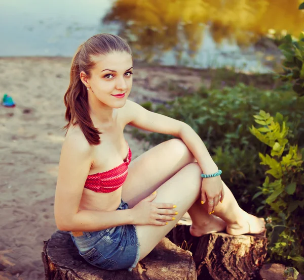 Hübsche Frau in der Natur, auf Baumstumpf sitzend — Stockfoto