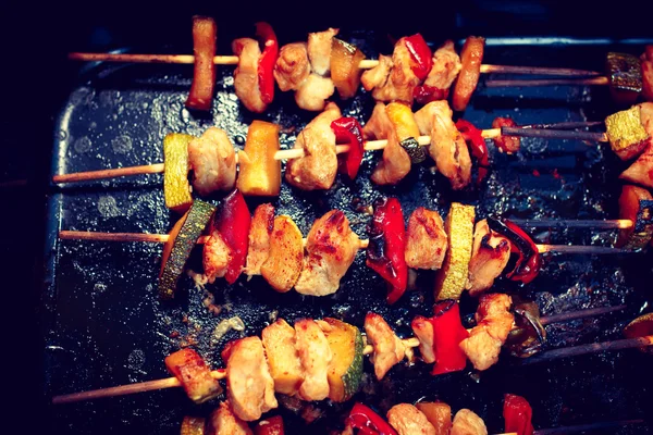 Chicken teriyaki kebabs with vegetables on black baking, toned — Stock Photo, Image