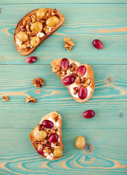 Pane tostato di segale e frumento con uva cotta sulla tavola blu Fotografia Stock