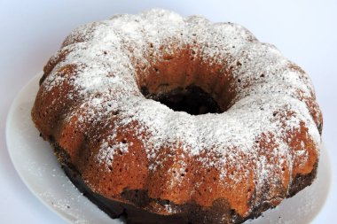 Bir ev yapımı Paskalya pastası pudra şekeriyle serpilmiş ve beyaz bir tabakta servis edilmiş, izole edilmiş.