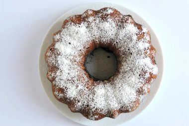 Bir ev yapımı Paskalya pastası pudra şekeriyle serpilmiş ve beyaz bir tabakta servis edilmiş, izole edilmiş.