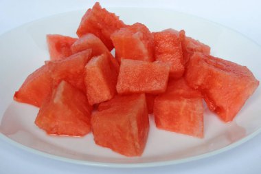 Beyaz tabaktaki olgun kırmızı karpuz küpleri, beyaz tabaktaki izole edilmiş.