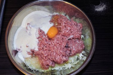 Biftek yapmak için kullanılan metal bir kasenin içindekiler: kıyma, mısır ezmesi, yumurta, doğranmış lahana.