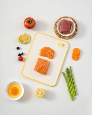 Çiğ Pişirme İçindekiler Somon Bifteği Sebzeleri ve Kesme Kurulu 'ndaki Meyveler Beyaz Arkaplan Fotoğrafı