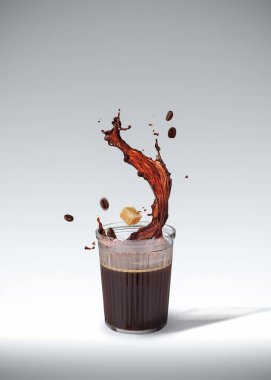 Uçan şeker küpü ve beyaz üzerine izole edilmiş kavrulmuş fasulye ile birlikte bardakta dinamik sıvı kahve sıçraması.