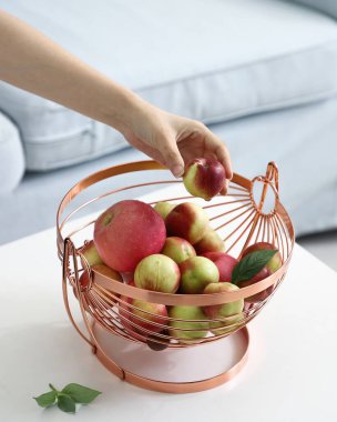 Taze nektarini, elma ve şeftali dolu gül sarısı bir meyve sepetine yerleştirirken.