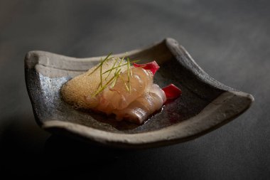 İnce dilimlenmiş çiğ balık sashimi, moleküler köpük ve bitki süslemesi içeren güzel deniz ürünleri mezeleri.