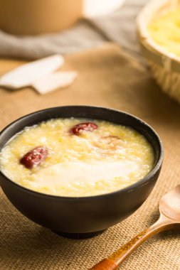 Kırmızı hurma ve yer elması ile besleyici çok tahıllı lapa sağlık ve sağlık için siyah bir kasede servis edilir.