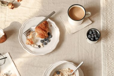 Sabah çayı ve kruvasan sahnesi çaydanlık ve reçel kavanozları yumuşak ışıkta, estetik katmanlı masa lambası bağcıklı masa örtüsü iç kısımda