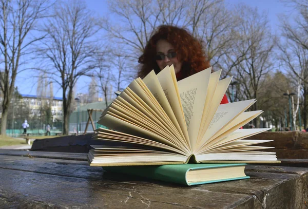 Frau schaut, wie der Wind ein Buch auflistet — Stockfoto