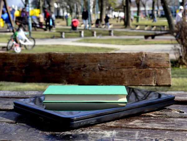 Woman in the park with a laptop and a book — Stock Photo, Image