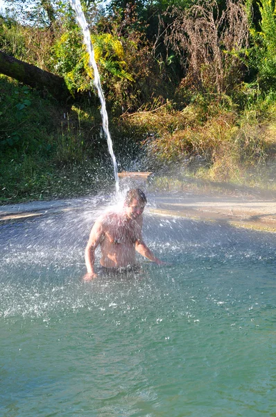 Un homme se tient dans la piscine avec de l'eau minérale sous le robinet — Photo