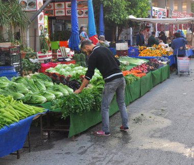ANTALYA, TURKEY - 10 Kasım 2017: Genç adam pazarda yeşillikleri seçiyor