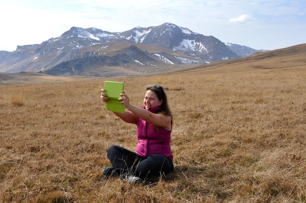 The girl looks in the Tablet PC near Mount Oshten — Stock Photo, Image
