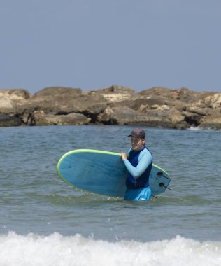 Tel Aviv, İsrail - 15 Ağustos 2021: Açık ve güneşli bir günde Tel Aviv 'de sörf yapan genç bir adam.