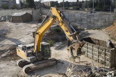 Hidrolik yakalama eklentisi olan bir kazıcı kullanarak yıkım atığı öğütücü.
