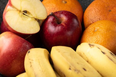 Üç üzüm, mandalina, muz ve elma, siyah bir tencerede.