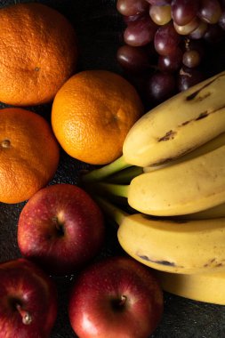 Üç üzüm, mandalina, muz ve elma, siyah bir tencerede.