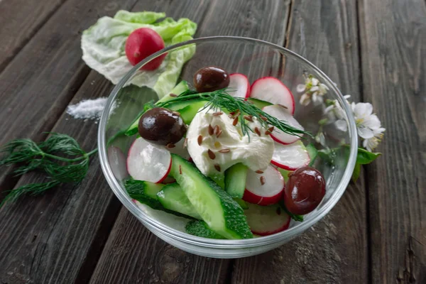 Top view of radish and cucumber salad in a glass bowl on wooden background — Stock Photo, Image