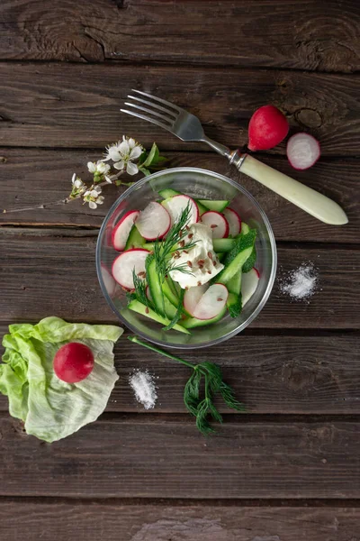 Top view of radish and cucumber salad in a glass bowl on wooden background — Stock Photo, Image