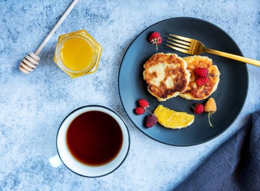 Süzme peynirli krep, Rus şurubu, böğürtlen, portakal ve bir fincan çay ile siyah tabakta. Bir kavanoz bal ve bal çubuğu. Kalsiyum açısından zengin sağlıklı bir kahvaltı..