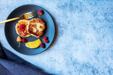 Süzme peynirli krep, Rus şurubu, böğürtlen ve portakallı siyah tabakta. Kalsiyum açısından zengin sağlıklı bir kahvaltı. Kopyalama alanı ile.