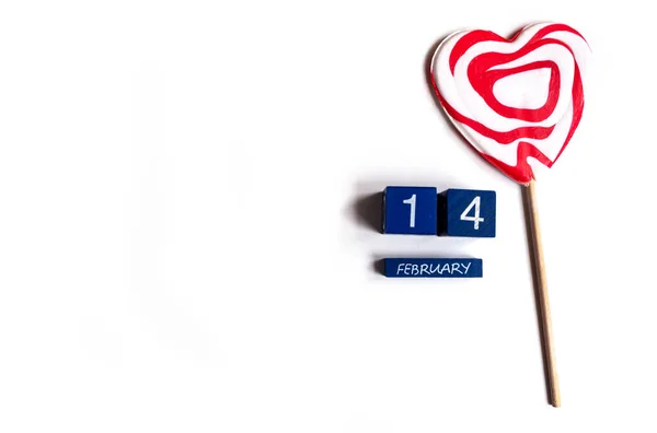 Top view of 14 February lettering and a heart-shaped lollypop on white background, copy space — Stock Photo, Image