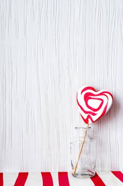 Cam kavanozda kalp şeklinde lolipop açık gri arka planda kırmızı beyaz masada sevgililer günü konsepti, kopyalama alanı