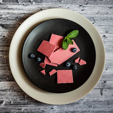 Pembe ya da yakut çikolata, siyah tabakta moda tatlı, ahşap gri arka plan, kare format.