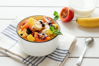 Bir kase taze meyve salatası ve hindistan cevizi gevreği ve yoğurt.