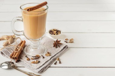Bir bardak aromatik baharat ve sütle demlenmiş sıcak Hint masala çayı. Beyaz tahta arkaplan, boşluğu kopyala